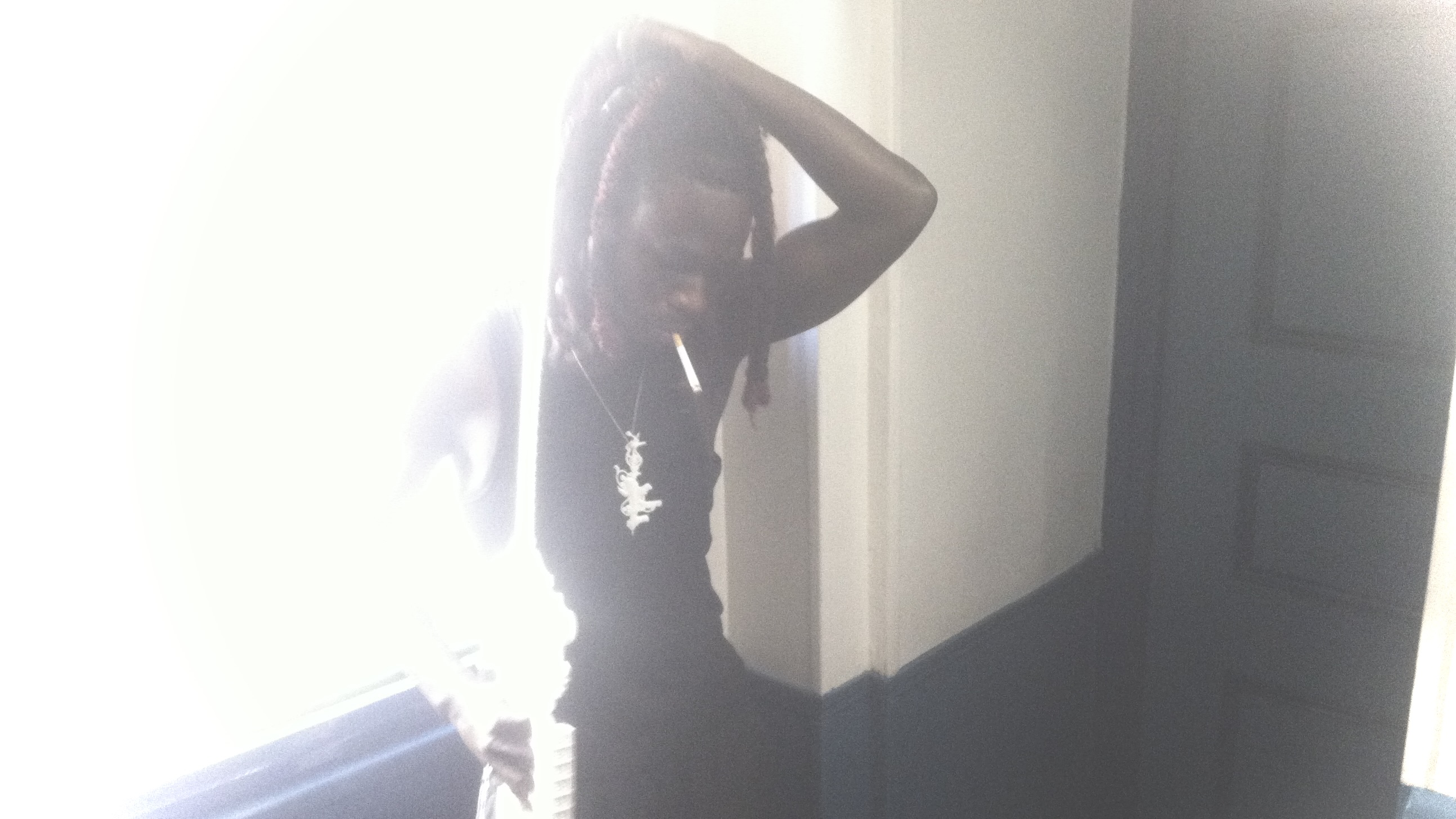 Portrait by a bright window, wearing a white sculptural pendant