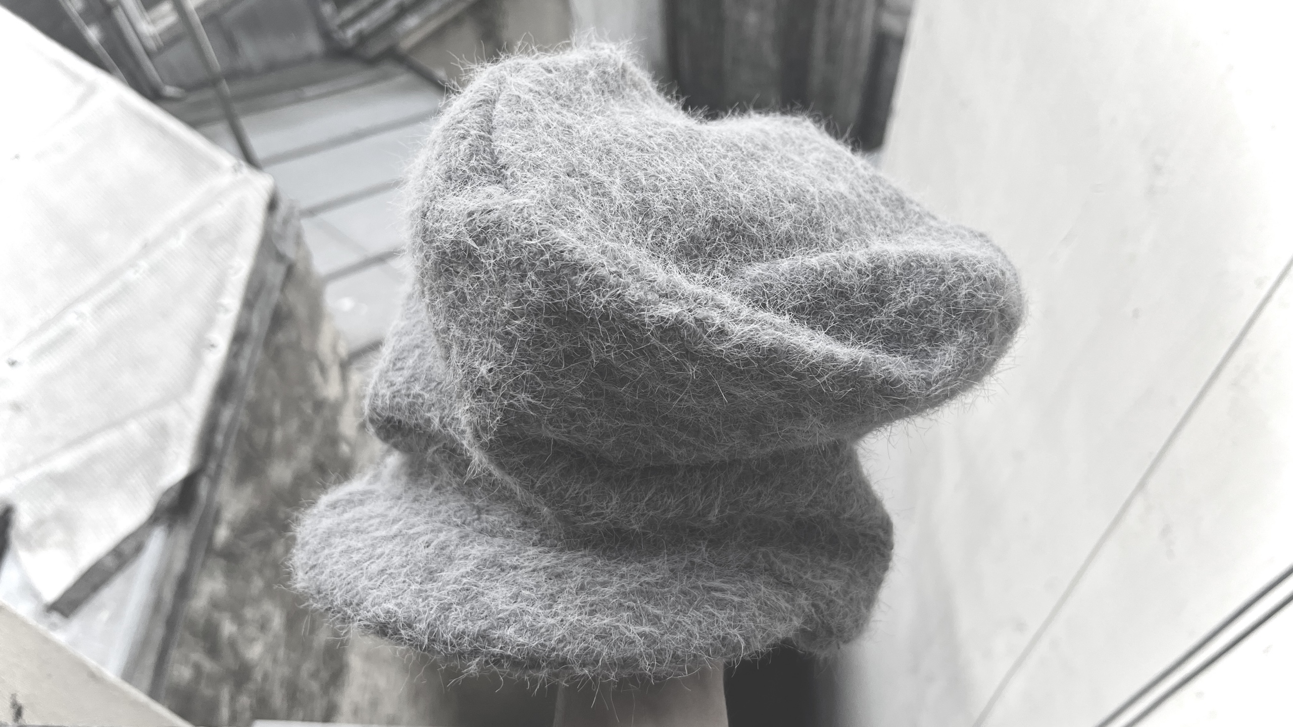 Soft grey sculptural knitted hat by a window