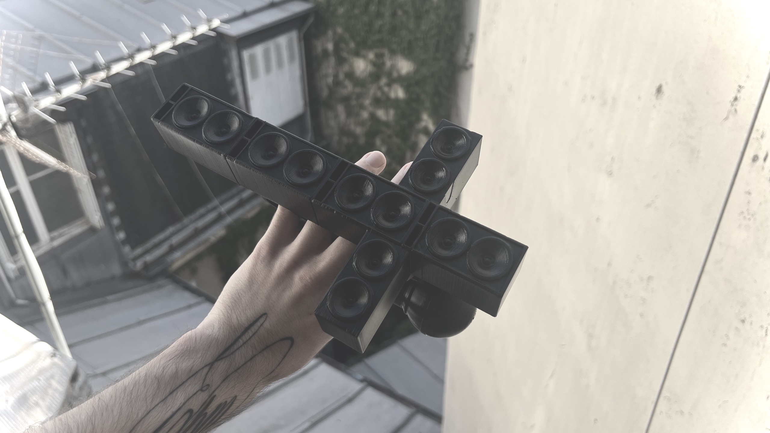 Black sculptural object with speaker-like details held beside a window