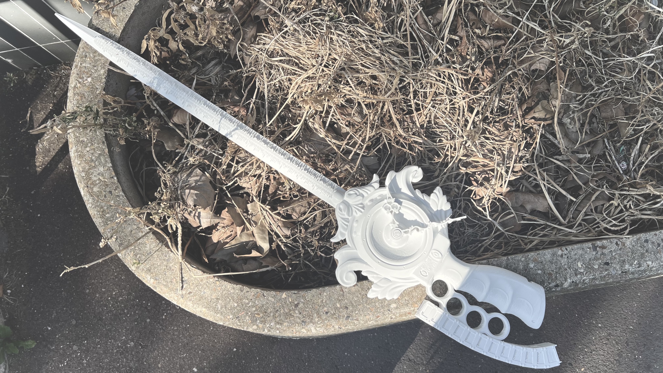 Ornate white sculptural object resting beside dry leaves outdoors